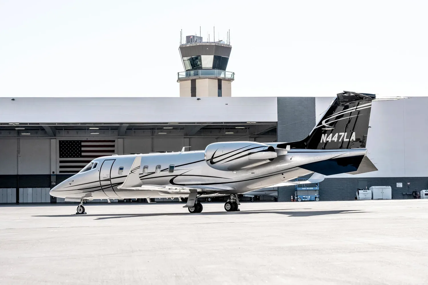 Learjet 45XR, registration N447LA, parked on the tarmac with an airport control tower in the background.