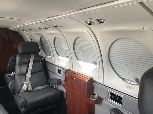 View of the aircraft's interior with leather seats and window shades.