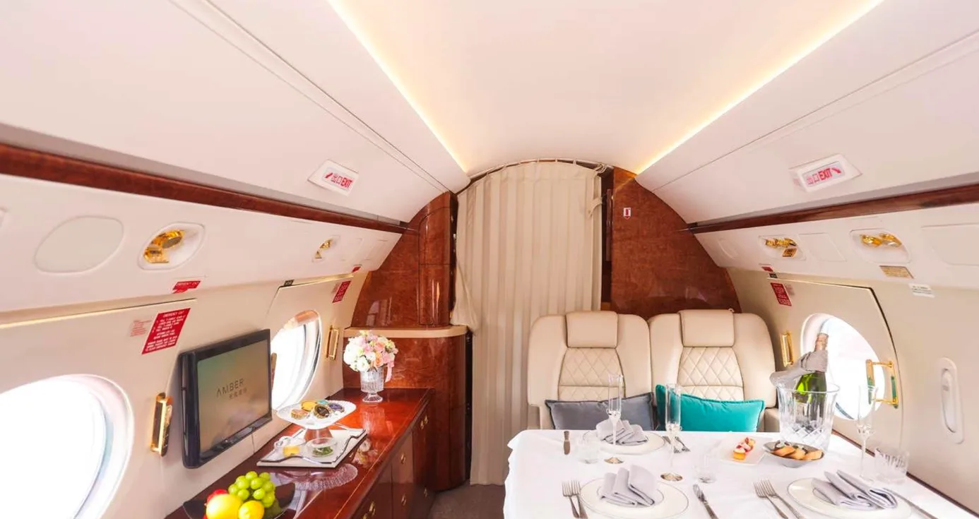 Interior of a private jet with a dining table and entertainment system.