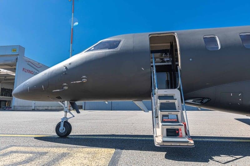 A Bombardier Challenger 350 aircraft with registration LX-VGF is parked on the tarmac at an airport with the stairs down.