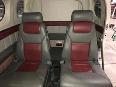 The interior of the aircraft features gray and maroon leather seats.