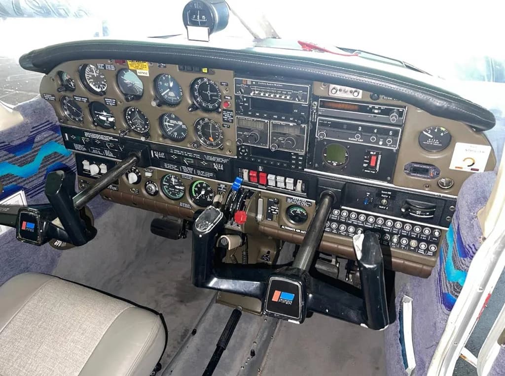 A wide view of the Piper aircraft's cockpit, featuring the instrument panel, control yokes, and front seats.
