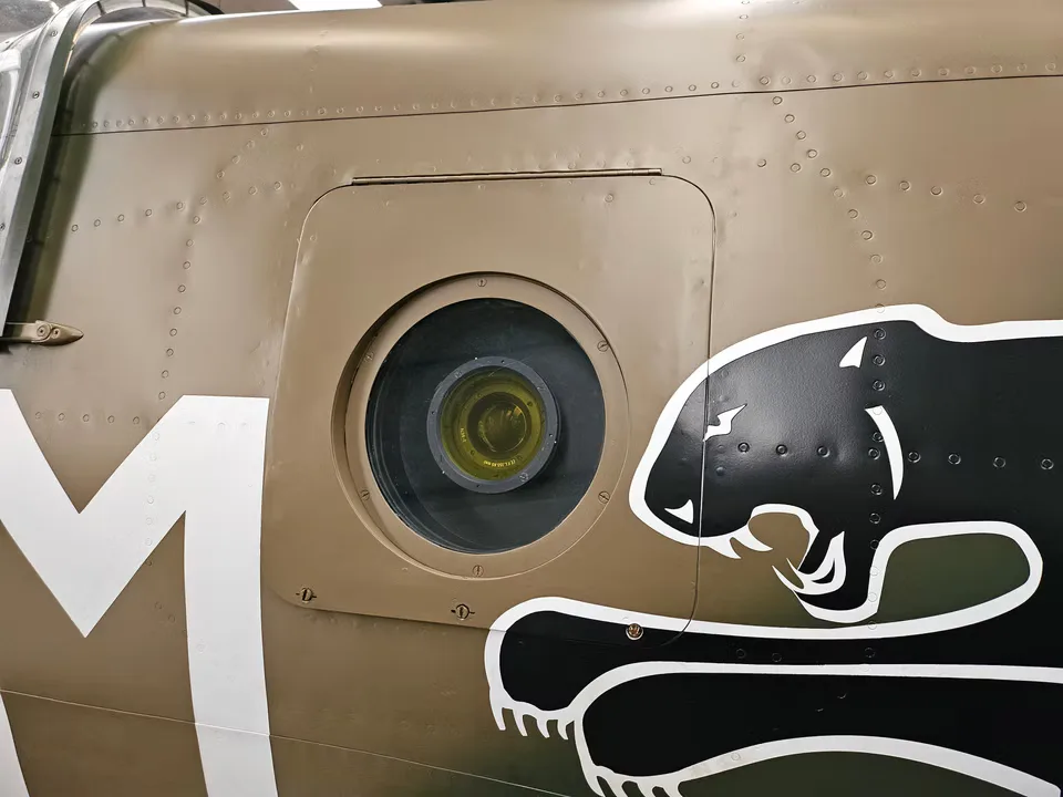 A close-up of the Supermarine Spitfire's fuselage, featuring a circular camera port and a black panther emblem.