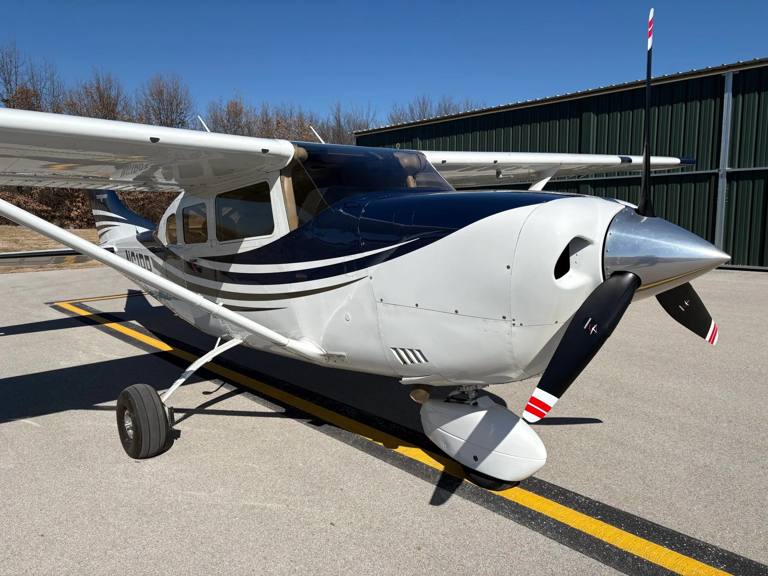 Three-quarter front view of a white and dark blue Cessna Stationair TC aircraft with registration N61RR on an airfield.