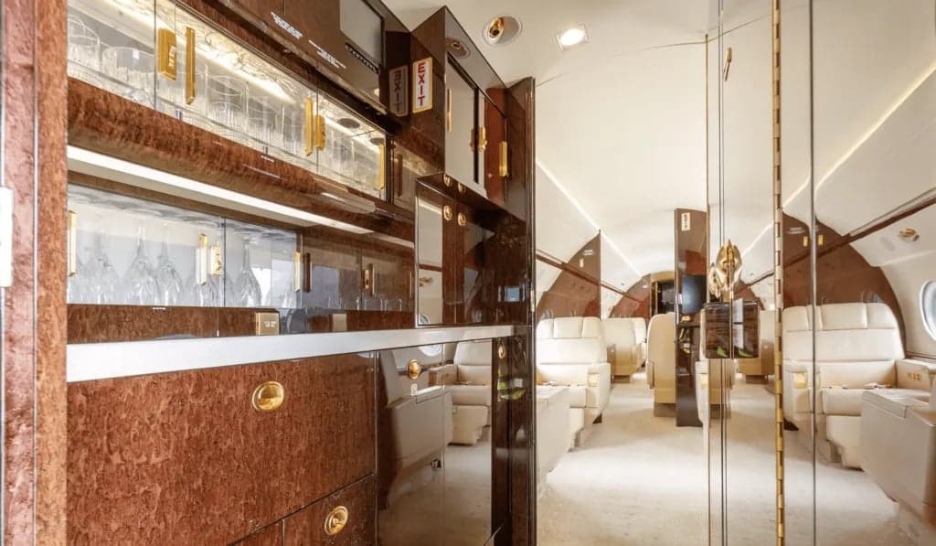 Interior view of the aircraft cabin with a bar area and beige leather seats.