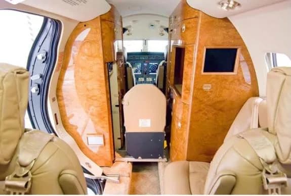 The interior of the aircraft features wood paneling and tan leather seats.