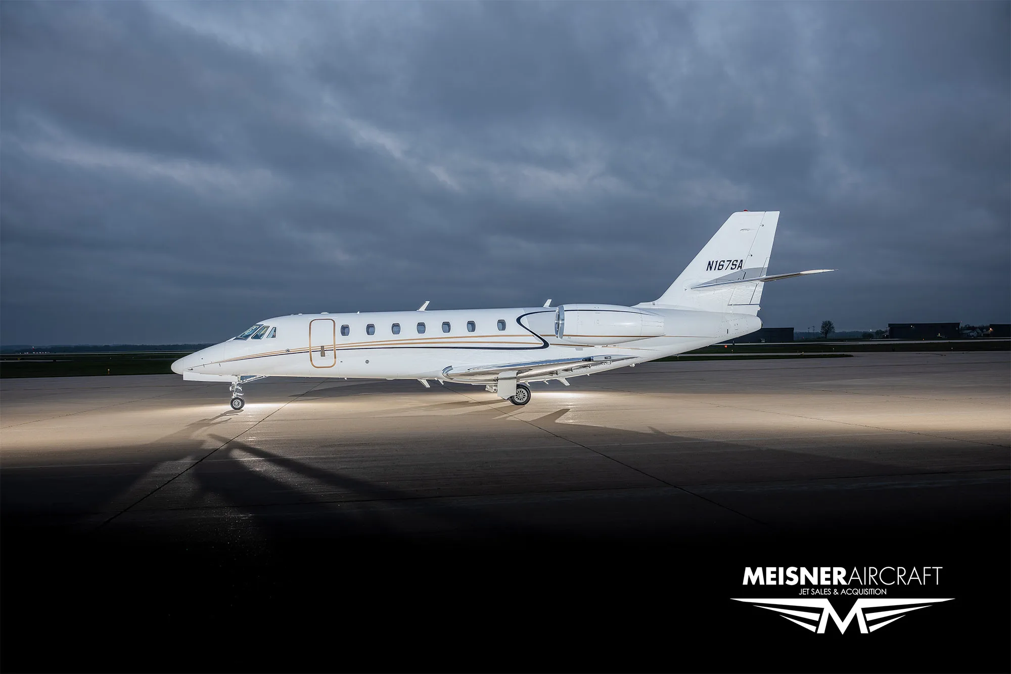 A side view of a white Cessna Citation business jet with tail number N167SA on an airfield at dusk.