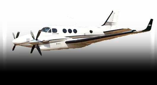 A white twin-turboprop aircraft, likely a Beechcraft King Air, with dark brown and gold stripes, viewed from the front-left side against a white background.