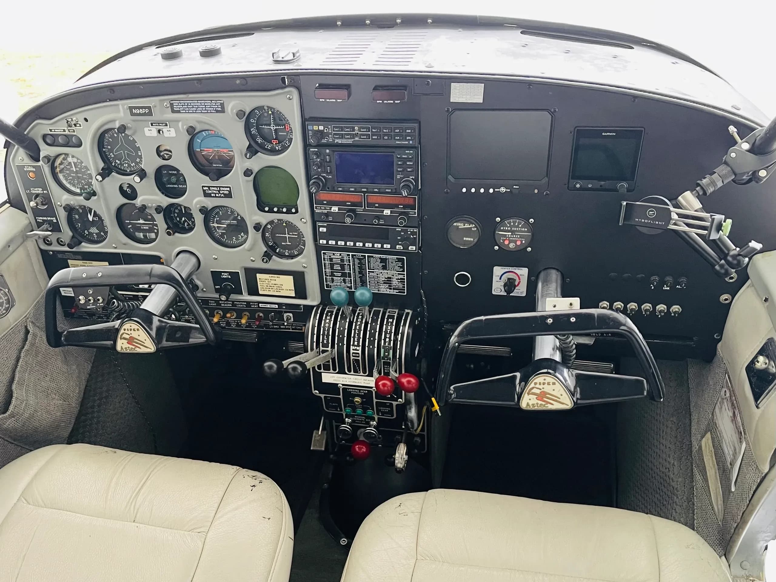 A detailed view of the aircraft's cockpit with instrument panel, dual yokes, and white leather seats.