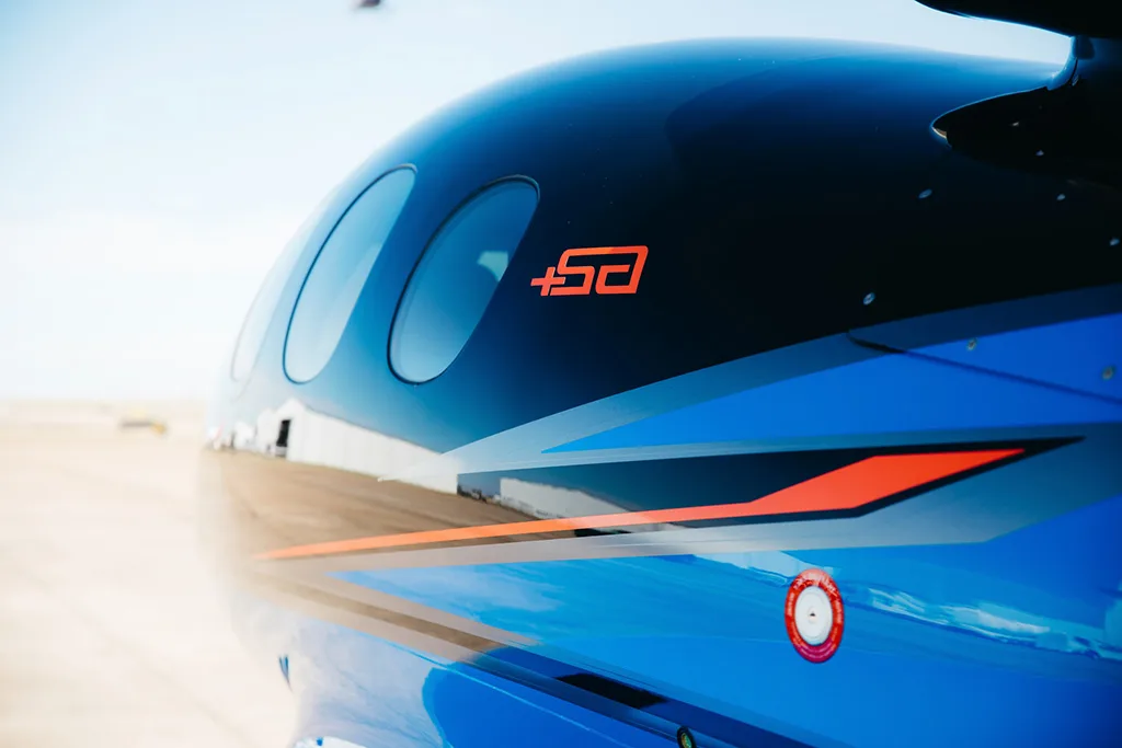 A close-up of the black and blue fuselage of a Cirrus Vision Jet (SF50) showing the "+50" logo.
