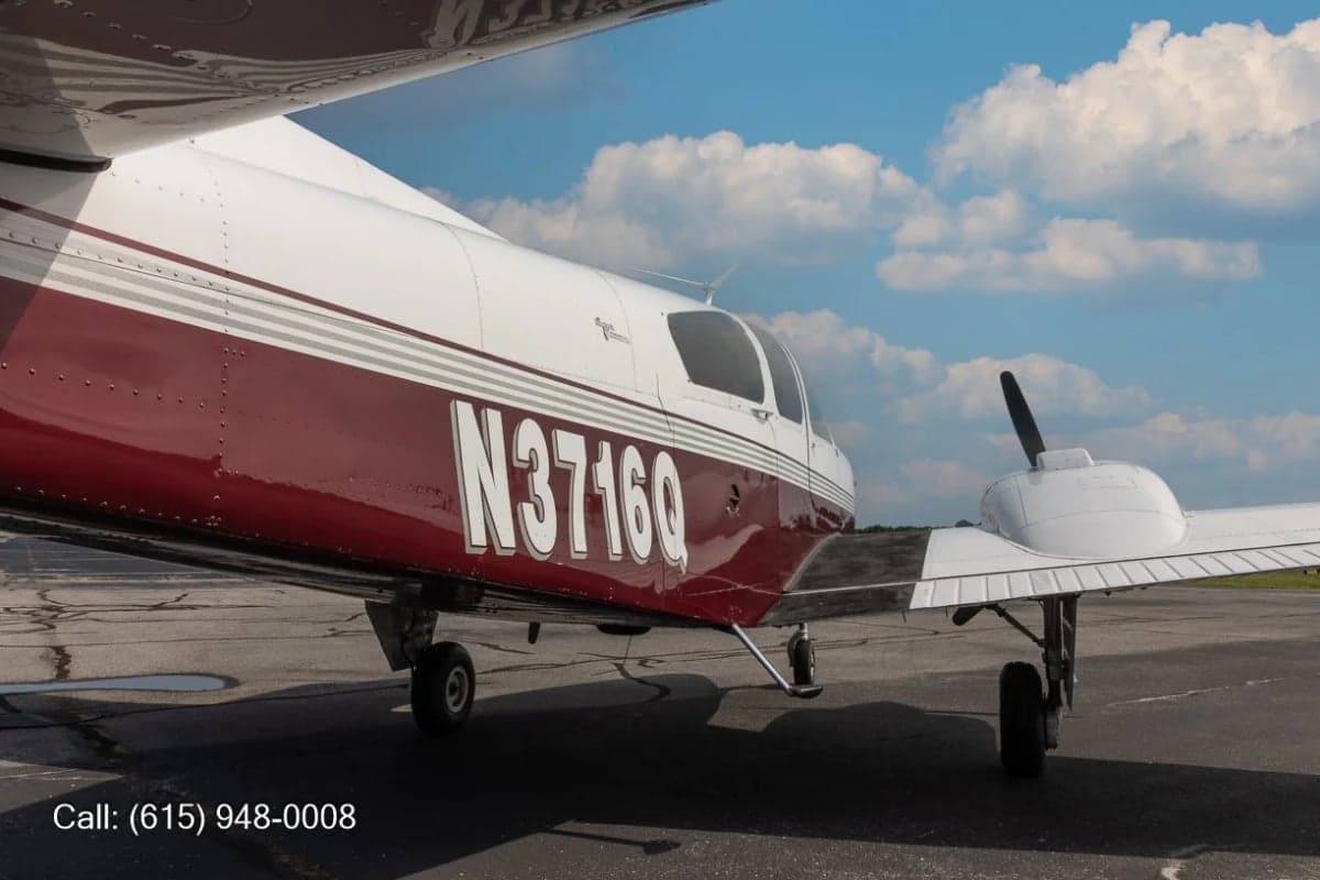 A rear-quarter view of a white and red twin-engine propeller aircraft with registration N3716Q, parked on an asphalt ramp.