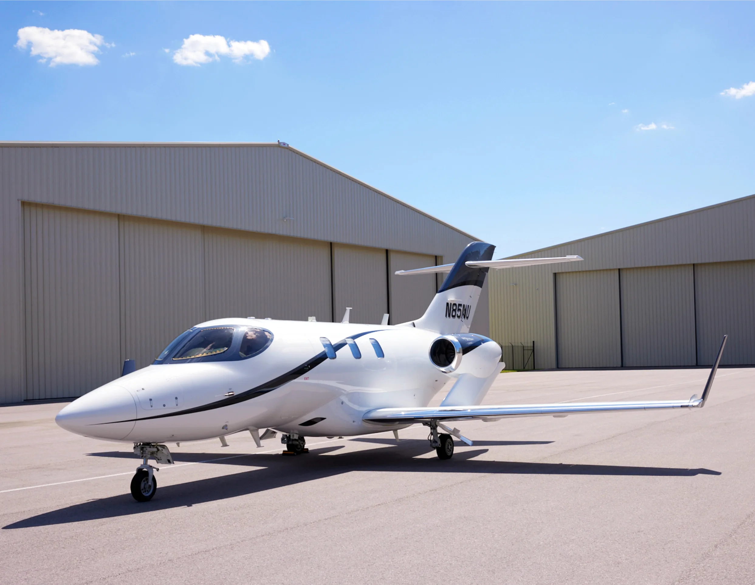 Side view of a white and black HondaJet N85NI on the tarmac.