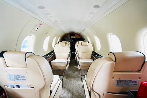 The interior of the aircraft features cream-colored leather seats and an exit sign.