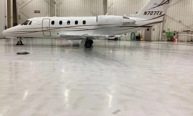 A white Cessna Citation business jet with gold and brown stripes, registration N727TX, parked in a hangar.
