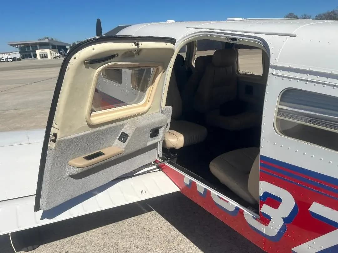 A red and white aircraft, N3258H, with its main cabin door open, showing the beige interior seats.