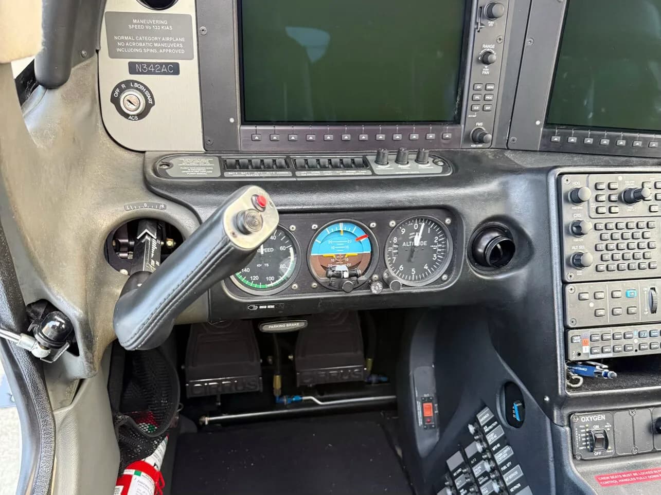 A close-up view of the left side of a Cirrus SR22 cockpit, showing the yoke, flight instruments, and registration N342AC.