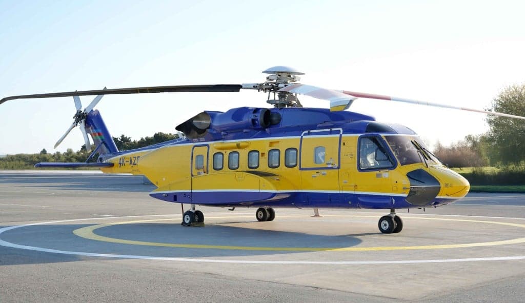 A close-up of the front of a blue and yellow helicopter on the ground.