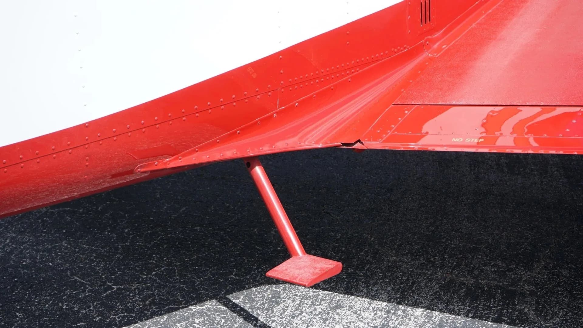 A close-up of the red underside of the aircraft's wing and a small red step on the fuselage.