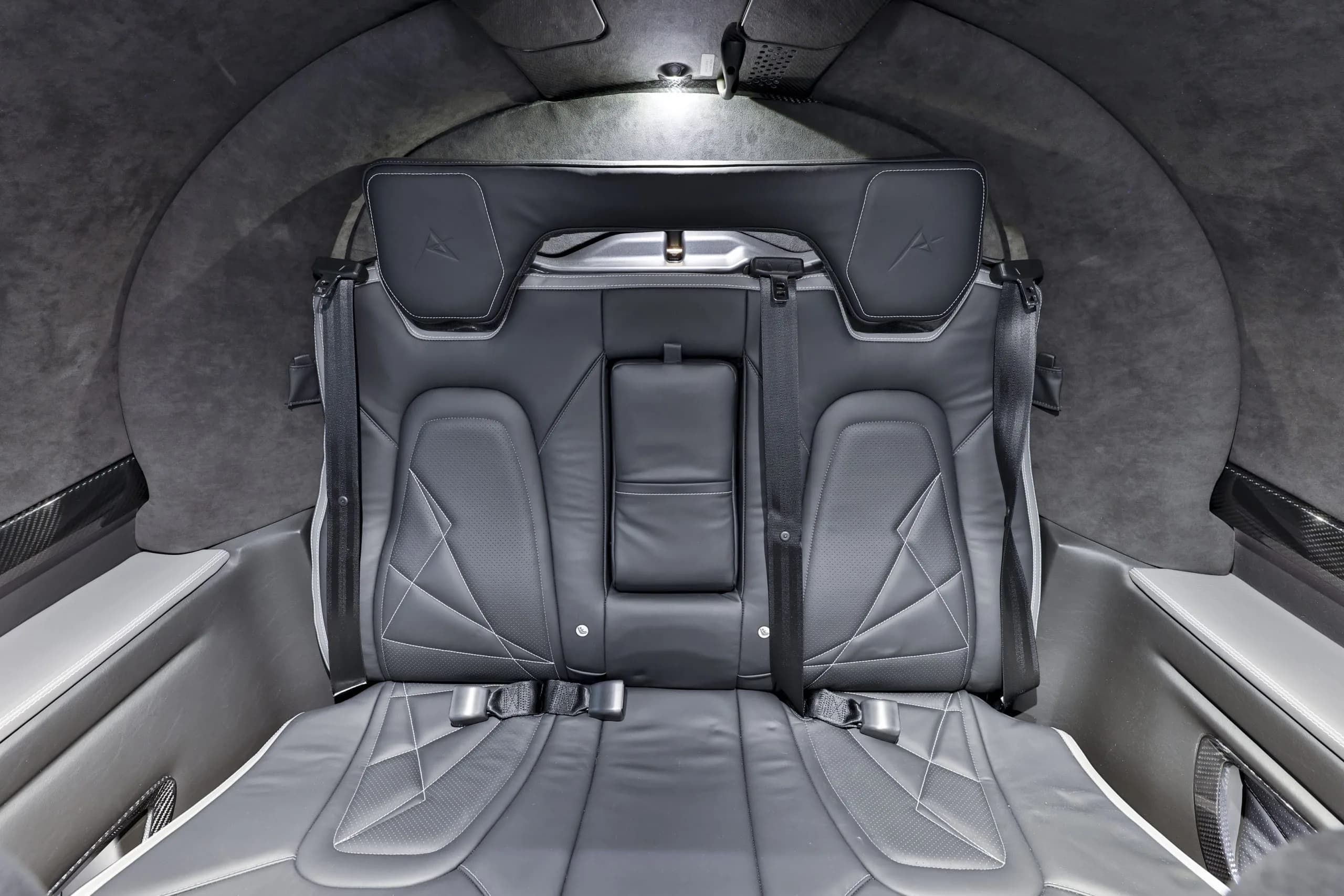 The rear bench seat of the Cirrus Vision Jet cabin is upholstered in dark grey leather with white stitching.