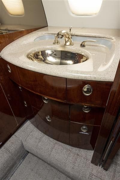 The aircraft's interior features a sink and vanity with wooden cabinetry.
