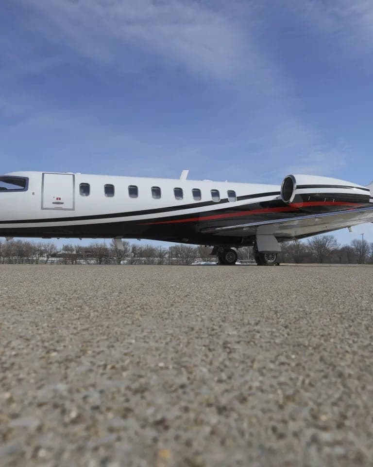 Side view of an aircraft with a white and black paint scheme on the tarmac.