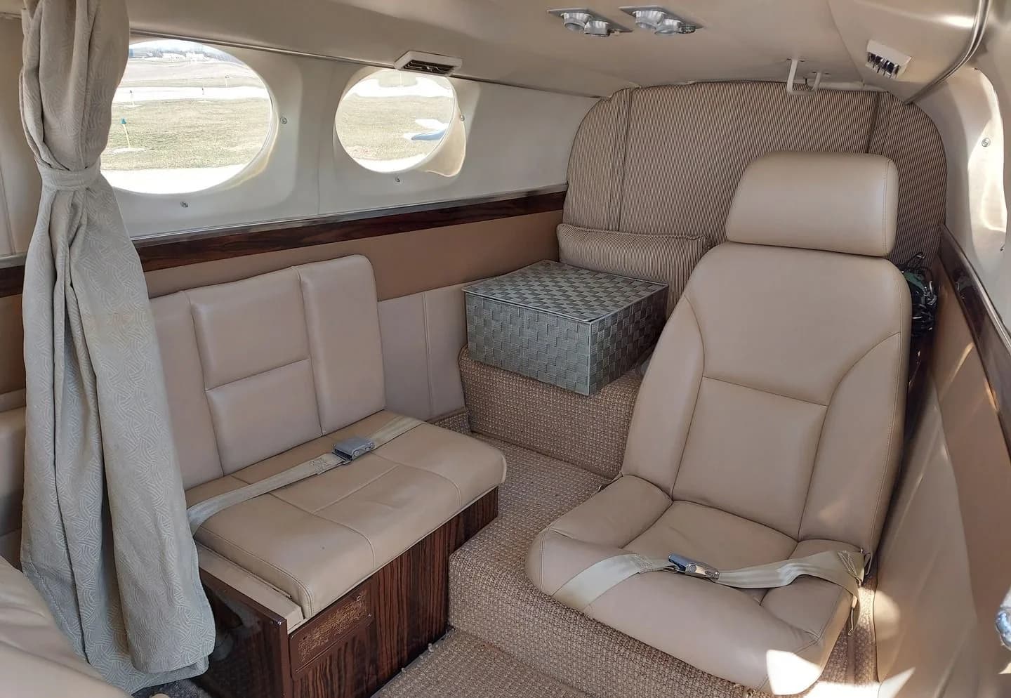 Interior of a Cessna 414 aircraft with tan leather seats and wood trim.