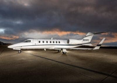A Learjet 45XR aircraft is parked on the tarmac at dusk.
