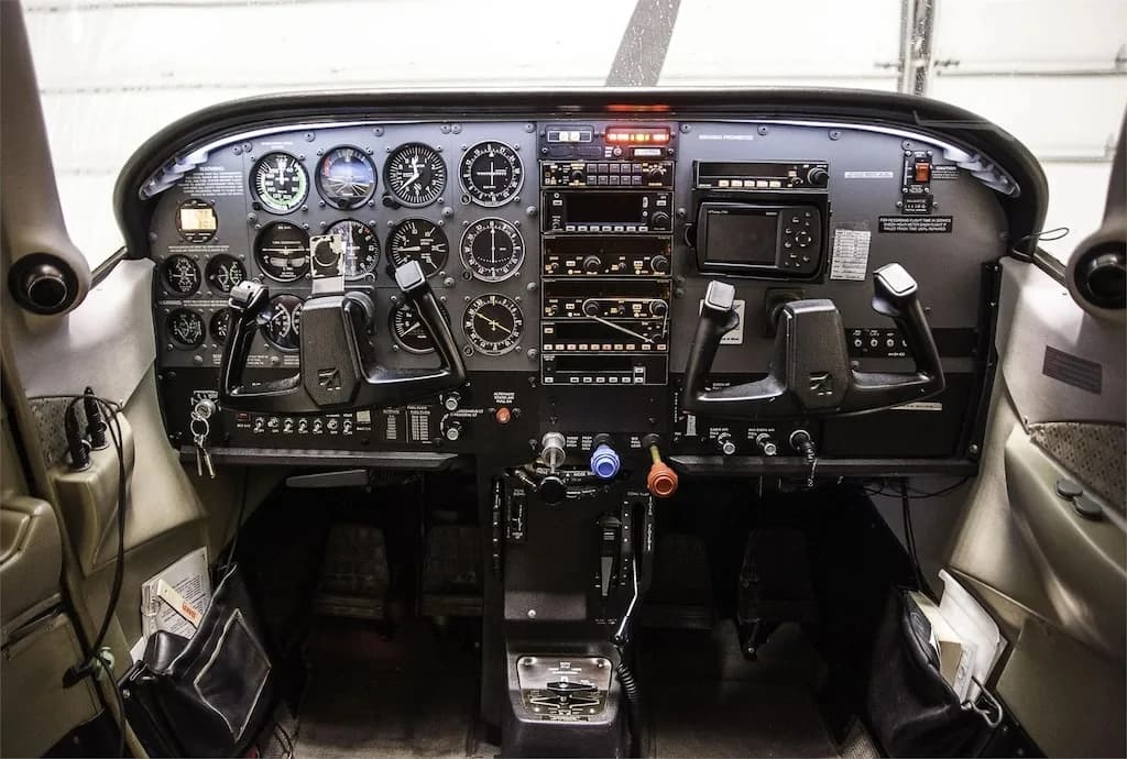 The detailed instrument panel and controls of a single-engine propeller aircraft cockpit.