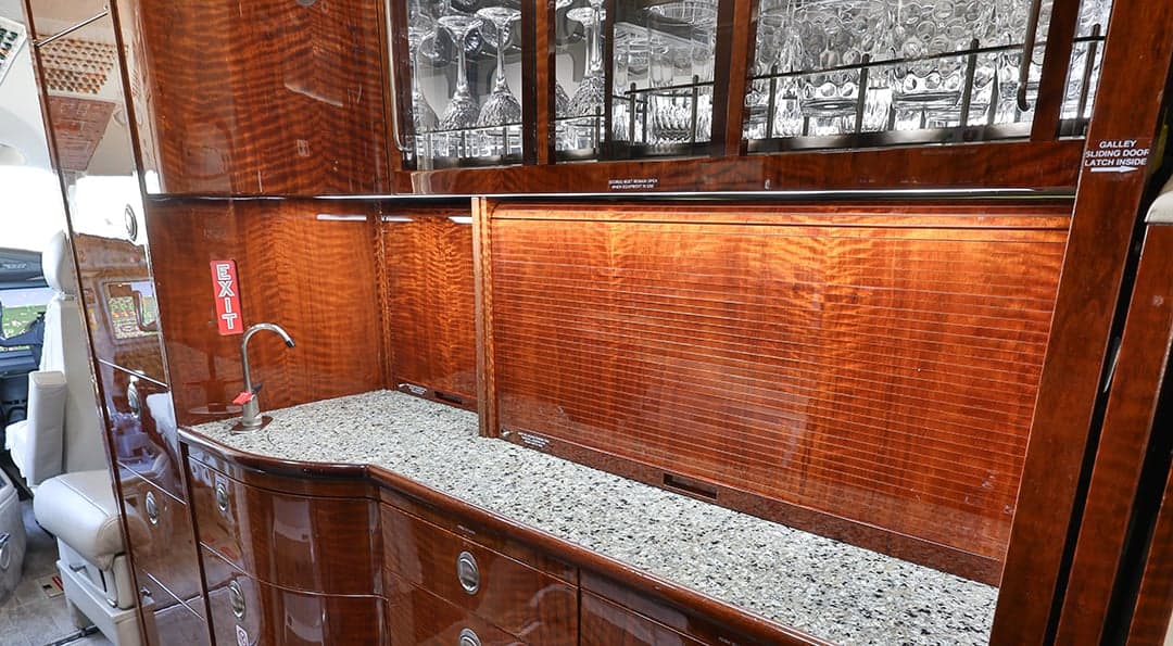 A galley area with wood cabinetry and a granite countertop.