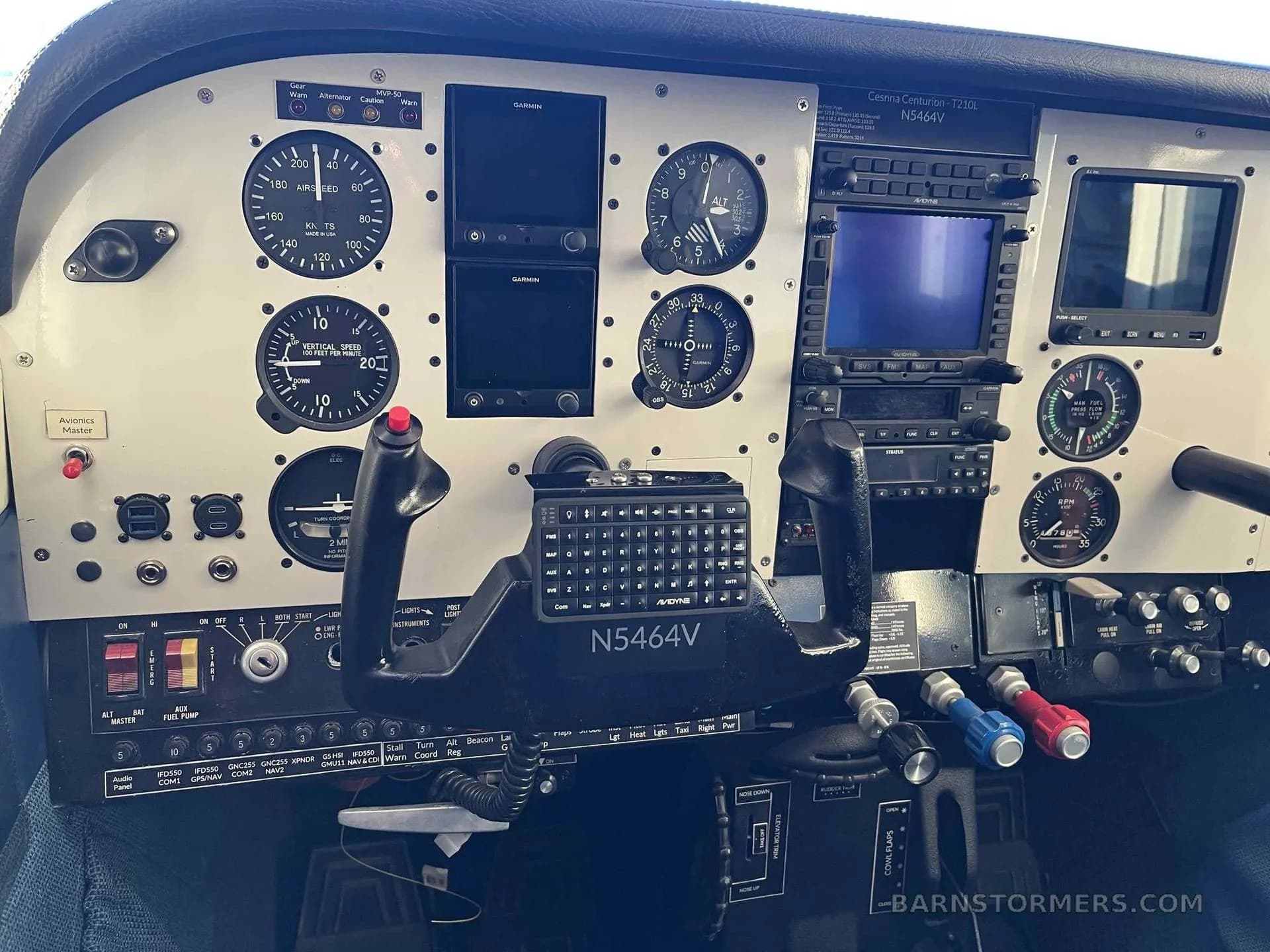 The cockpit of a Cessna Centurion 210L, showing the instrument panel with analog gauges and Garmin avionics, and the yoke with registration N5464V.