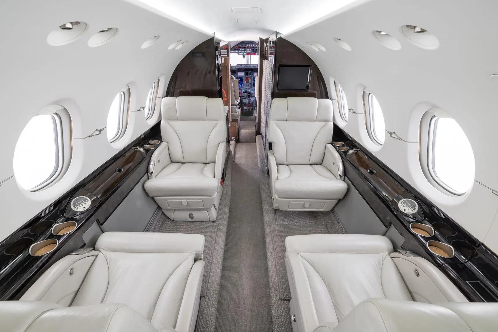 A view of the aircraft's cabin interior featuring light leather seats and a central aisle.