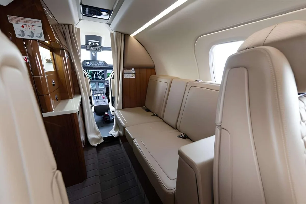 A view of the aircraft's interior cabin with leather seats and a view of the cockpit.