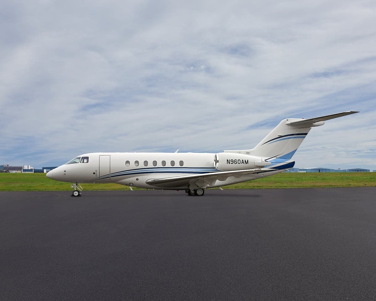 Side view of a white and blue Hawker 900XP aircraft on the tarmac.