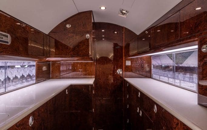 The interior cabin of a Gulfstream G450 aircraft with couches and a monitor.