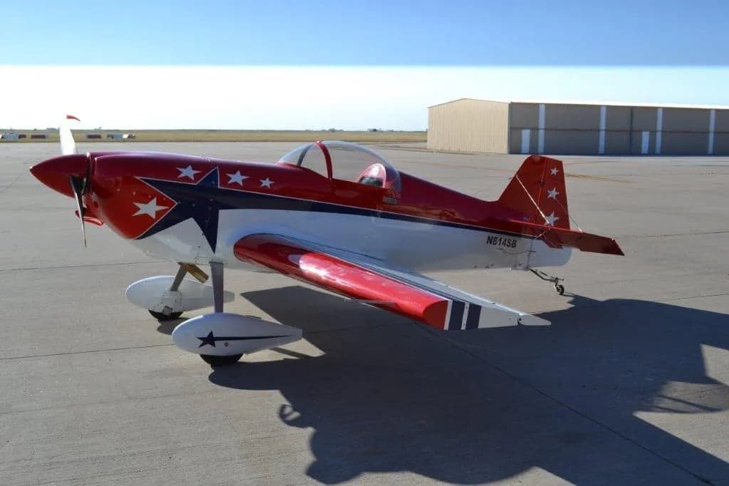A red and white aircraft with stars on the tail and wings is parked on the tarmac.