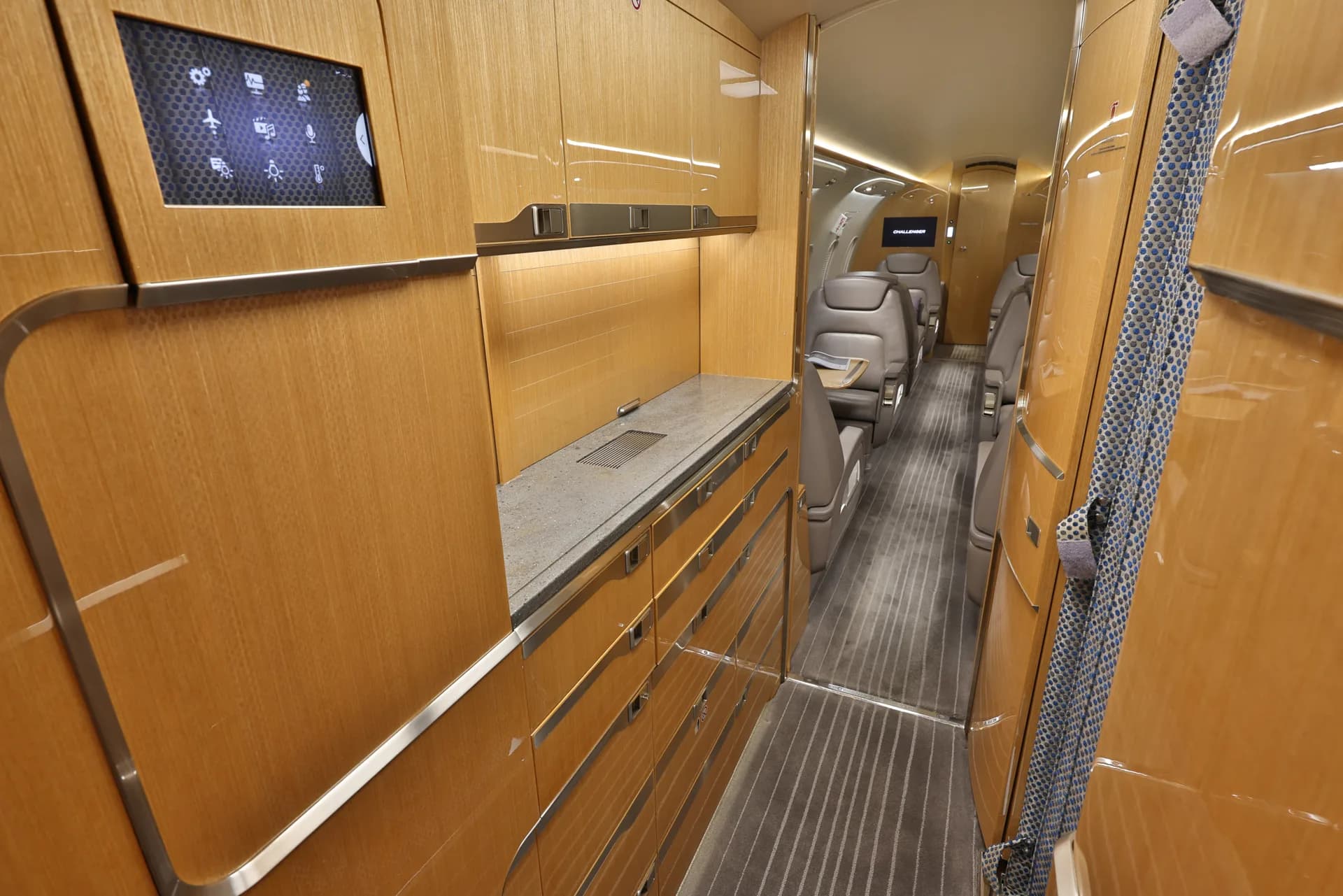 The interior of a Challenger aircraft with wood cabinetry and leather seats.