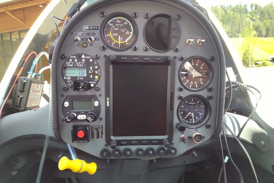 A glider with open cockpit parked on a paved surface.