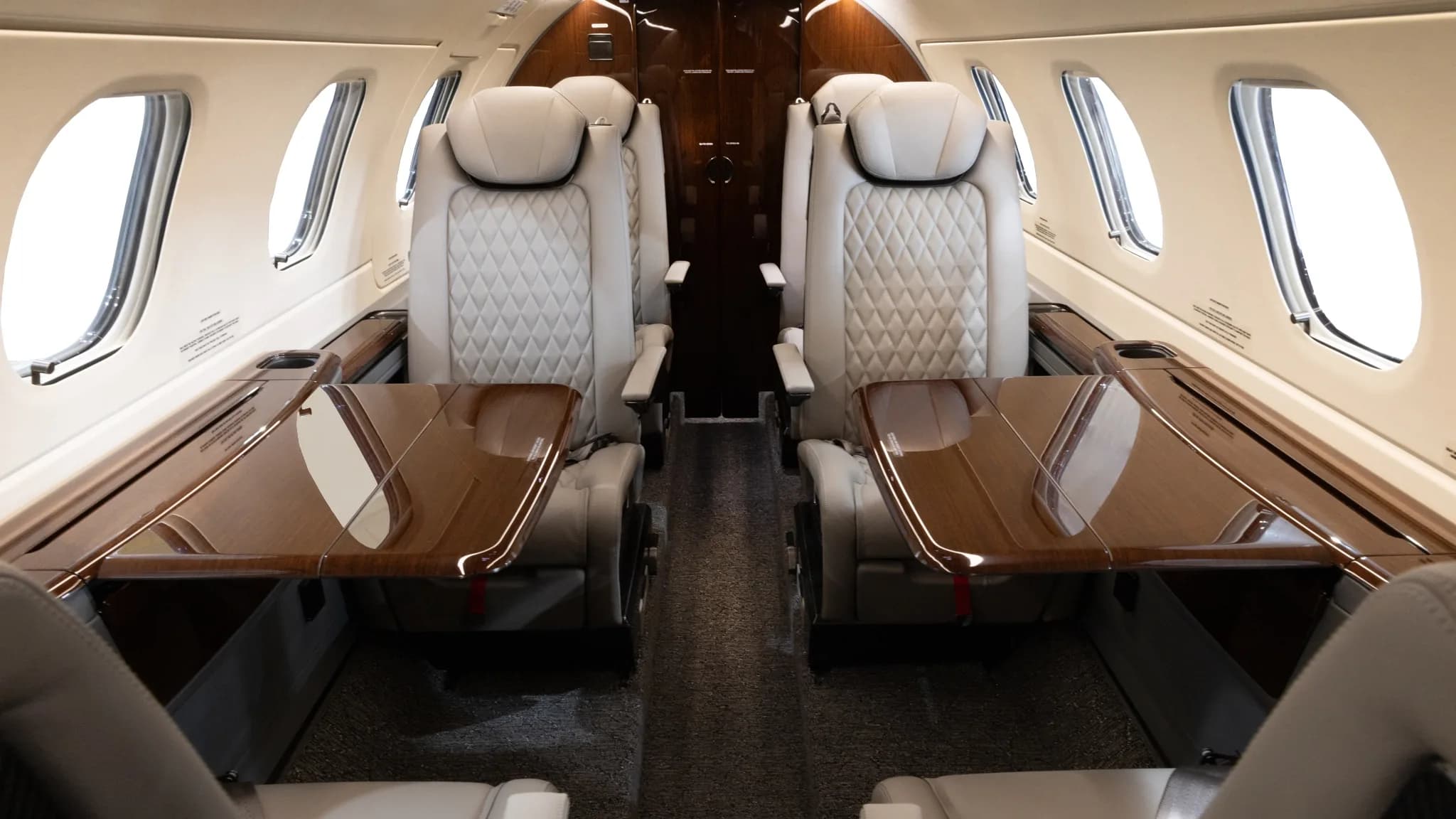 View of the aircraft cabin with leather seats and wood tables.