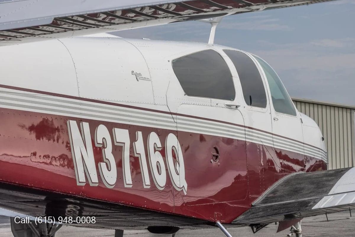A close-up side view of the fuselage of a white and red aircraft with registration N3716Q, showing the cockpit windows.