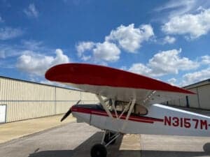 Close-up of the wing and fuselage of a Piper Cub aircraft.