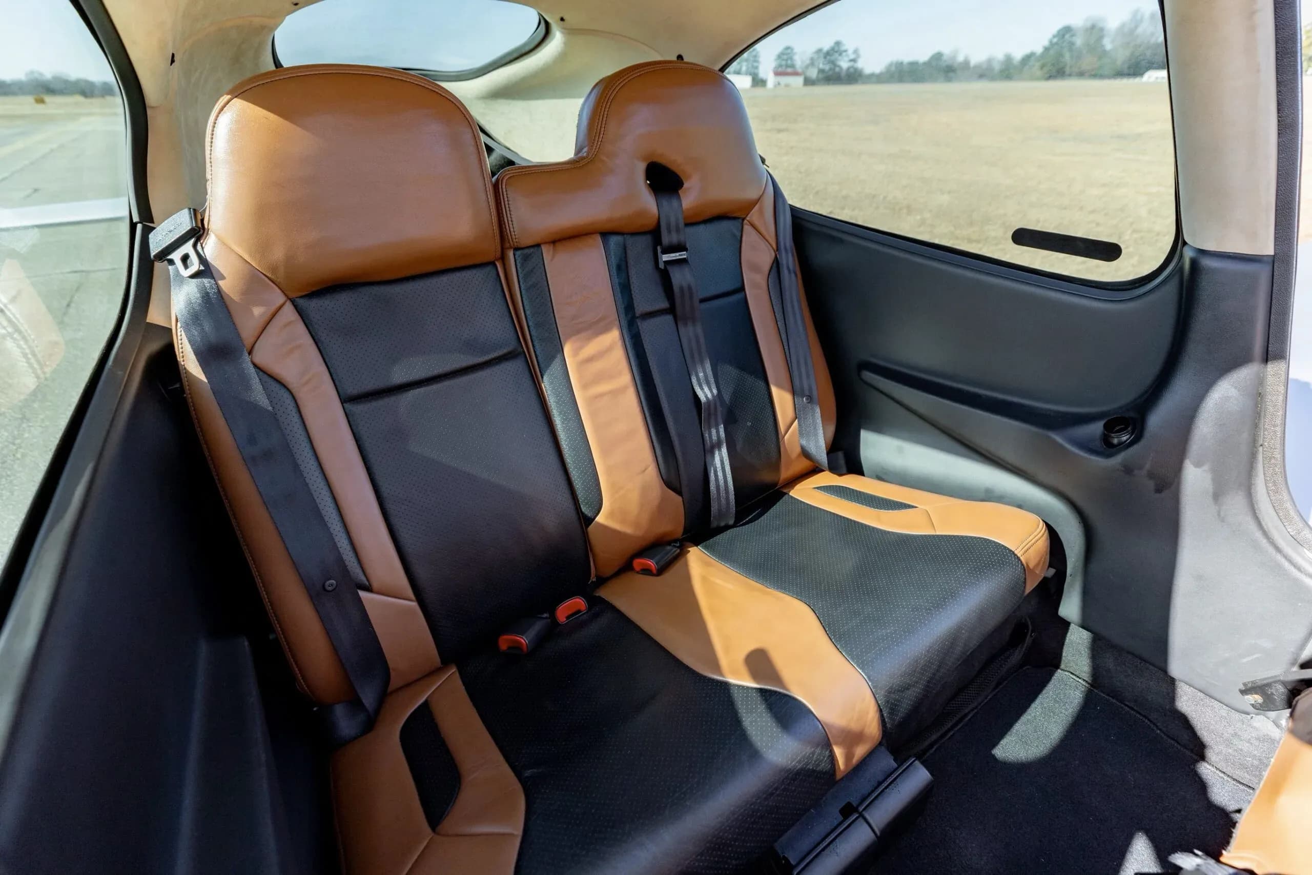 A side view of the two-tone brown and black leather rear seats in the Cirrus SR20 GTS aircraft cabin.