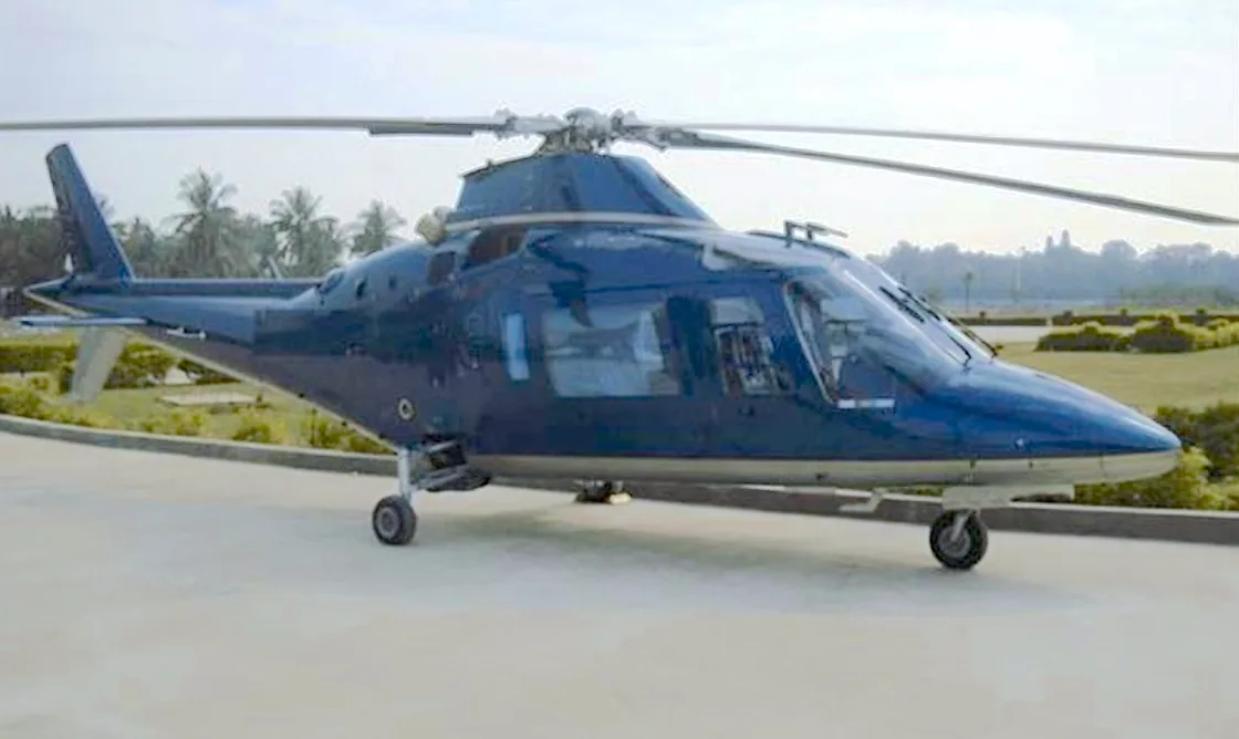 A dark blue AgustaWestland AW109 Power helicopter is parked on a helipad.