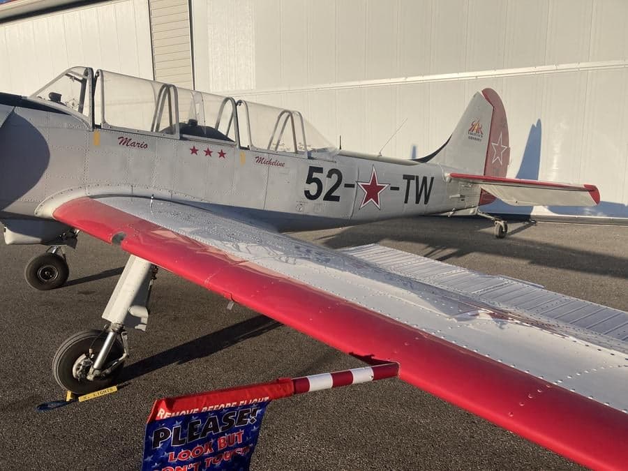 Close-up of the side of a Yak-52TW aircraft with red accents and markings.