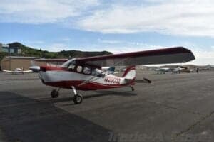A red and white Cessna aircraft parked on the tarmac at an airport.