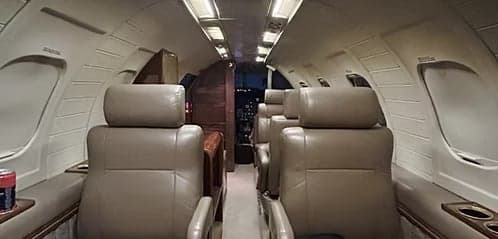 A view down the aisle of the aircraft cabin with leather seats.