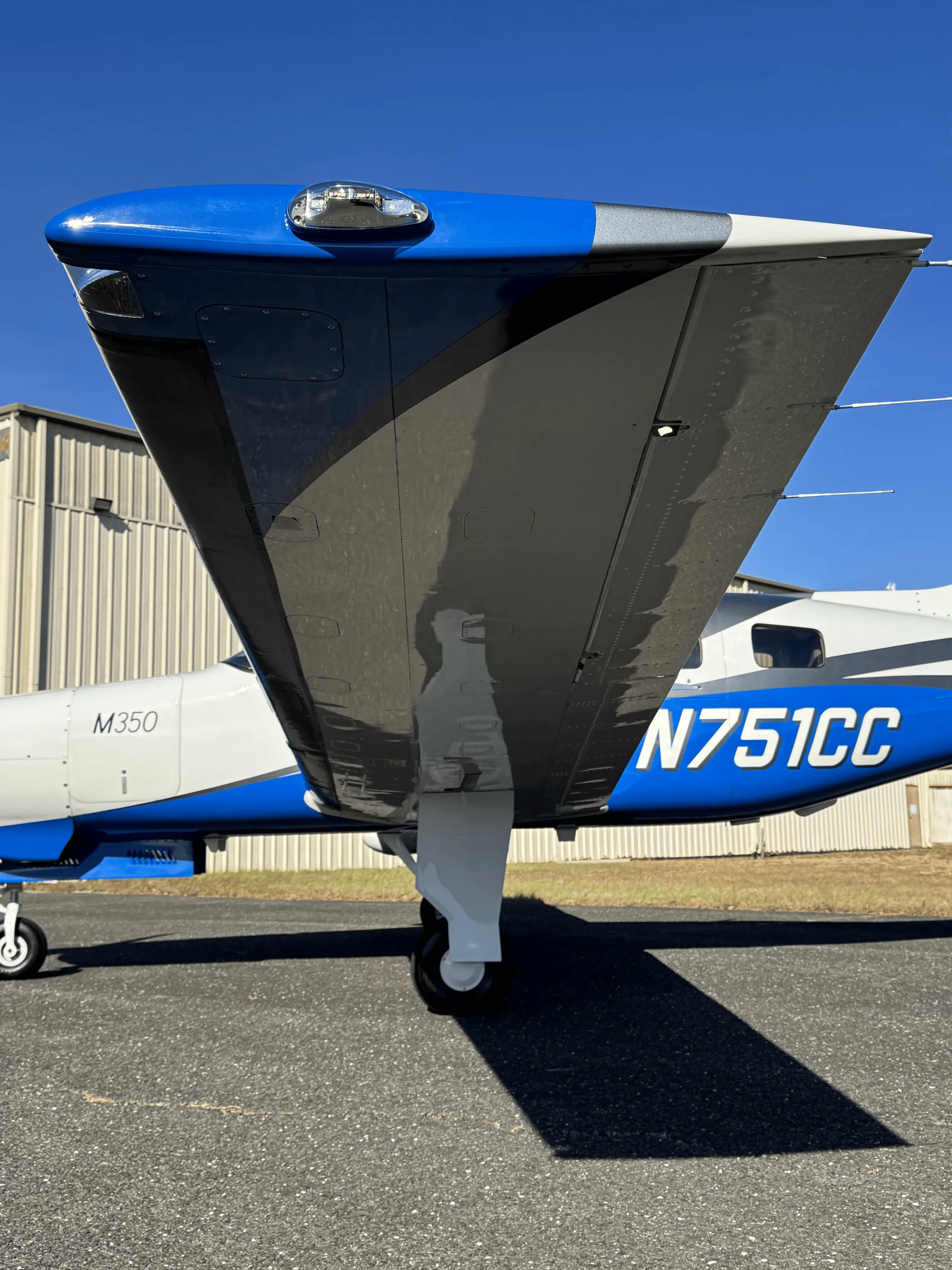 An underside view of the wing and fuselage of a Piper M350 aircraft, registration N751CC, showing the landing gear.