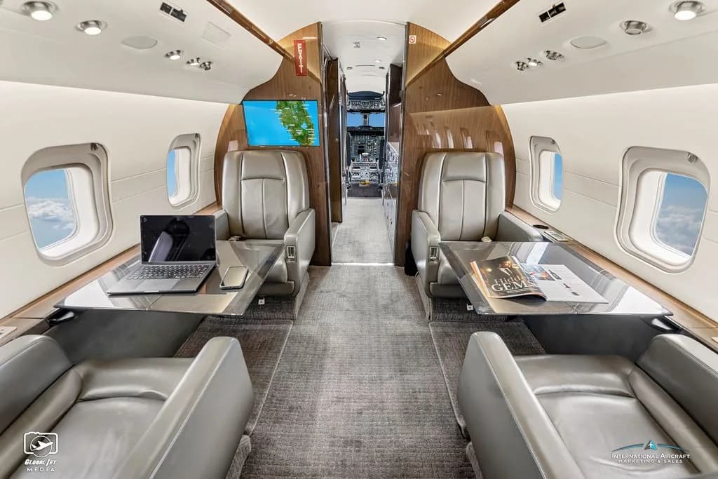 View of the Challenger aircraft cabin with leather seats and wood trim.