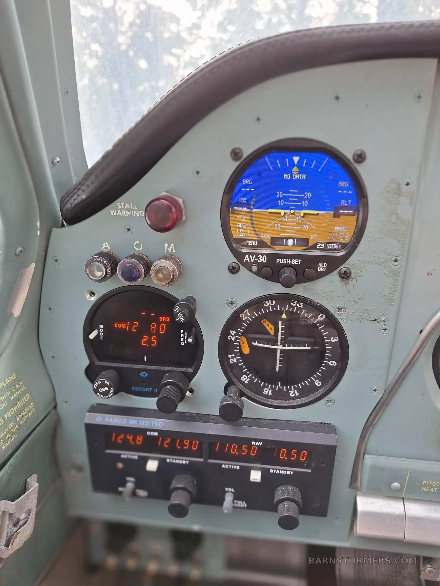 A close-up view of an aircraft's instrument panel, showing an AV-30 primary flight display, radios, and other gauges.