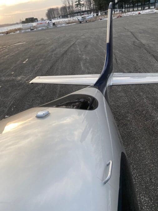 A view of the tail of a Cirrus aircraft on the tarmac.