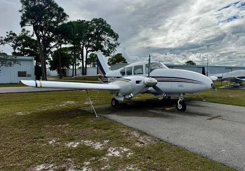 A white twin-engine aircraft with blue and gold stripes, registration N6375Y, parked on an asphalt ramp at an airfield.